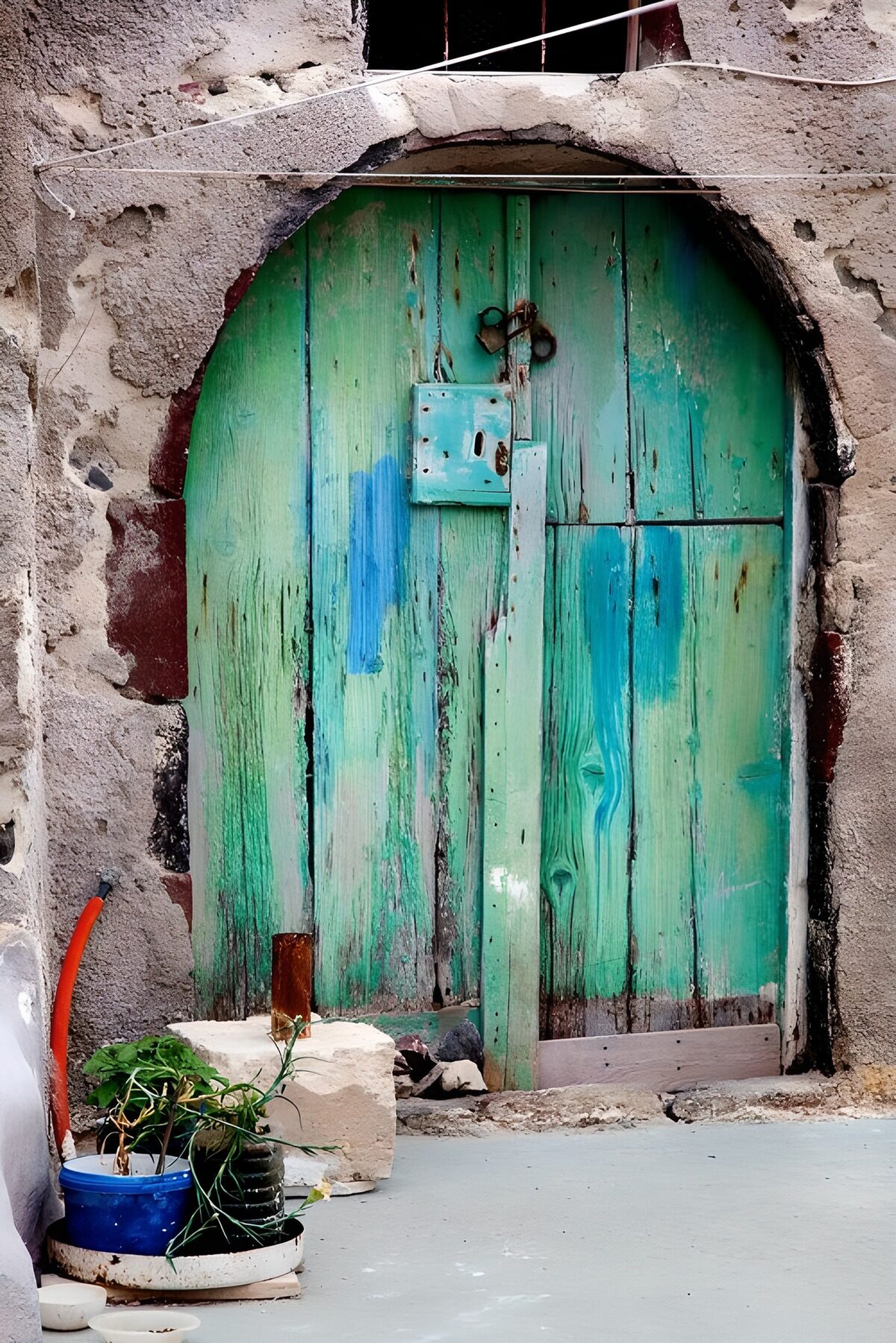 Verweerde turquoise deur onder een boog