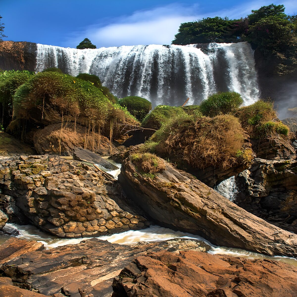 Brede waterval boven ruige rotsen