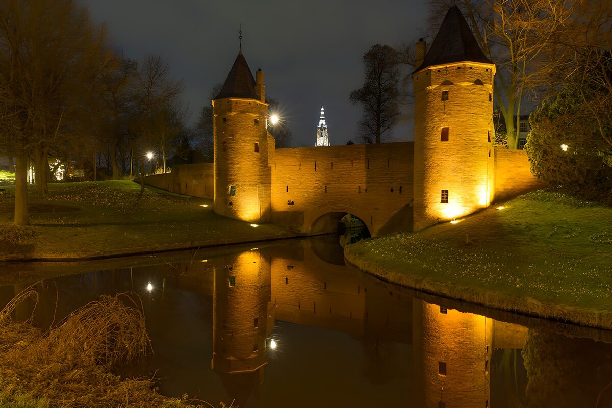 Verlichte stadspoort aan de gracht