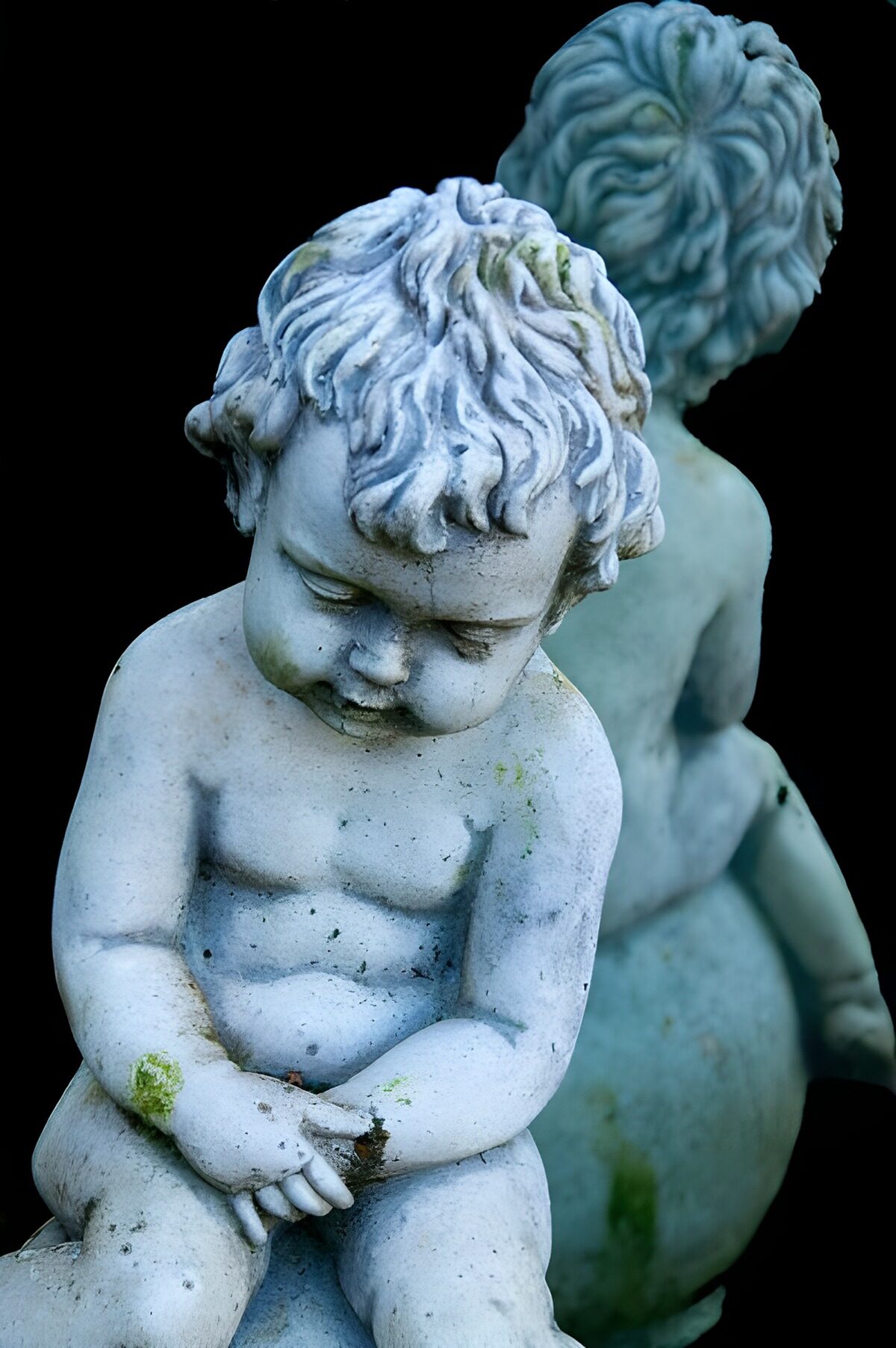 Twee verweerde stenen kinderbeelden