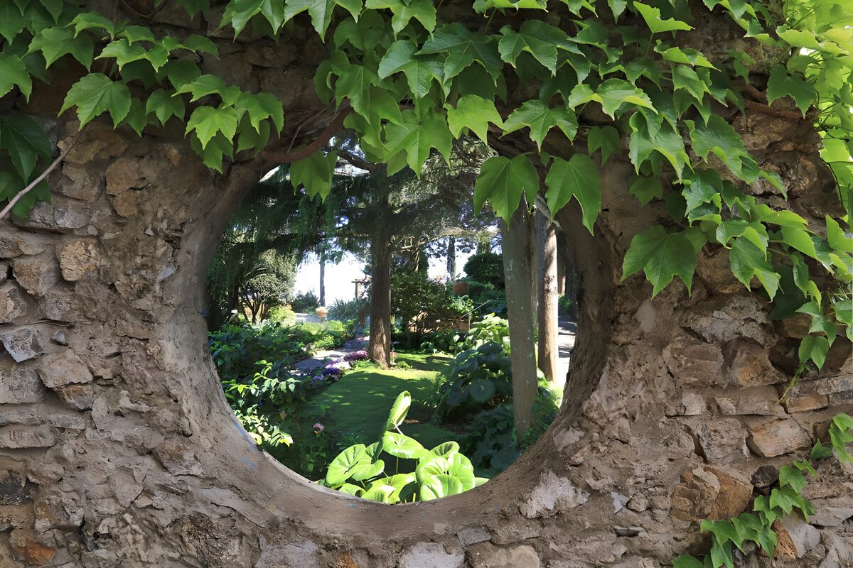 Ronde doorkijk in een begroeide tuinmuur