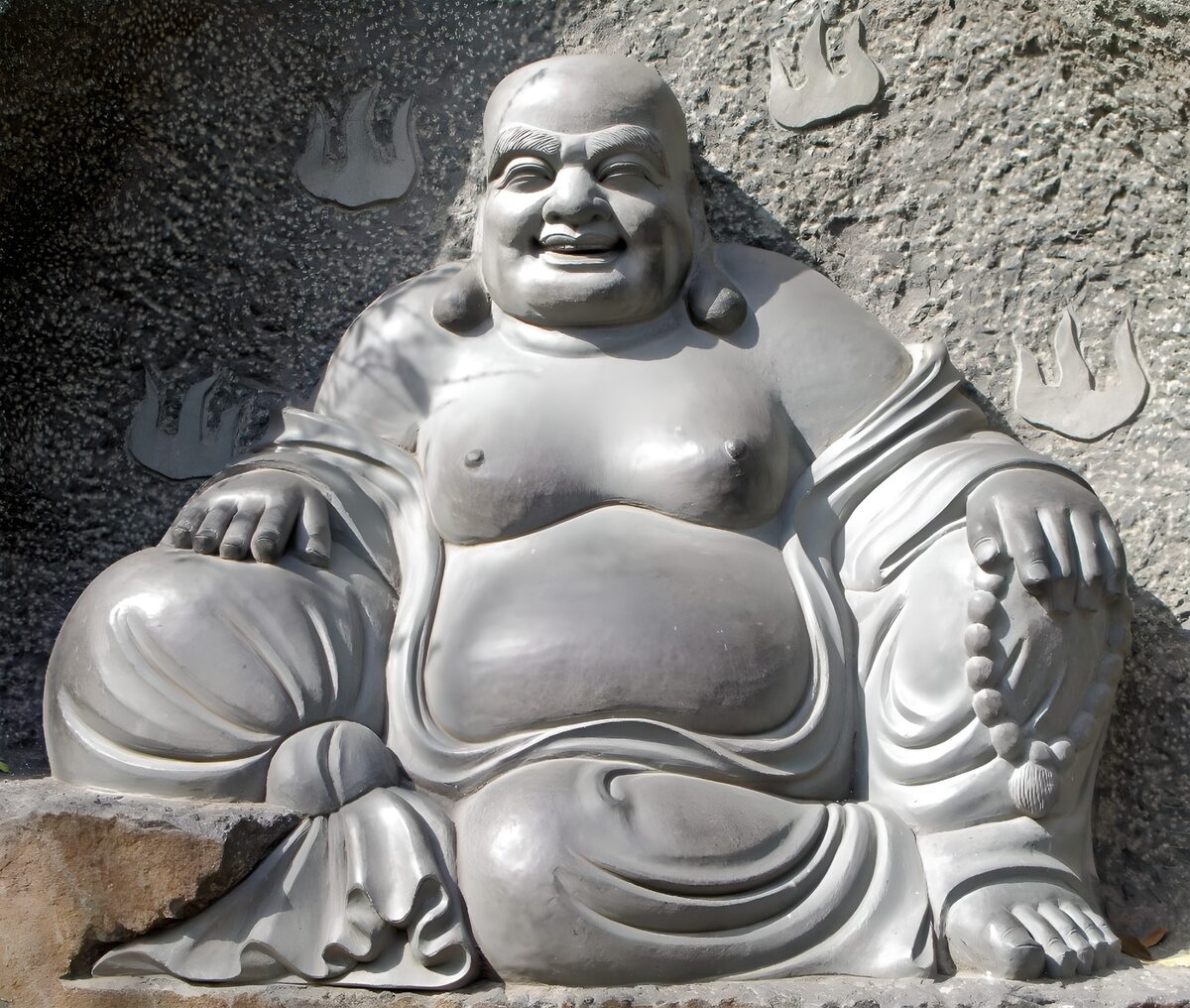 Lachende Boeddha in grijze steen