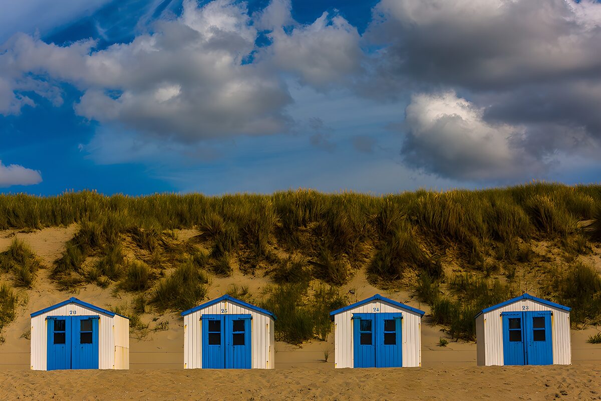 Vier blauw-witte strandhuisjes bij de duinen
