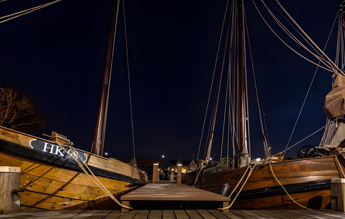 Houten zeilschepen aan de steiger bij nacht