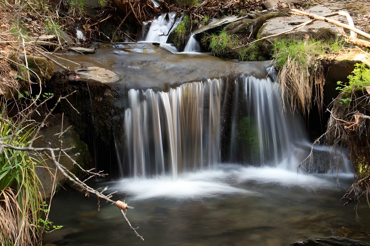 Kleine waterval tussen rotsen en gras