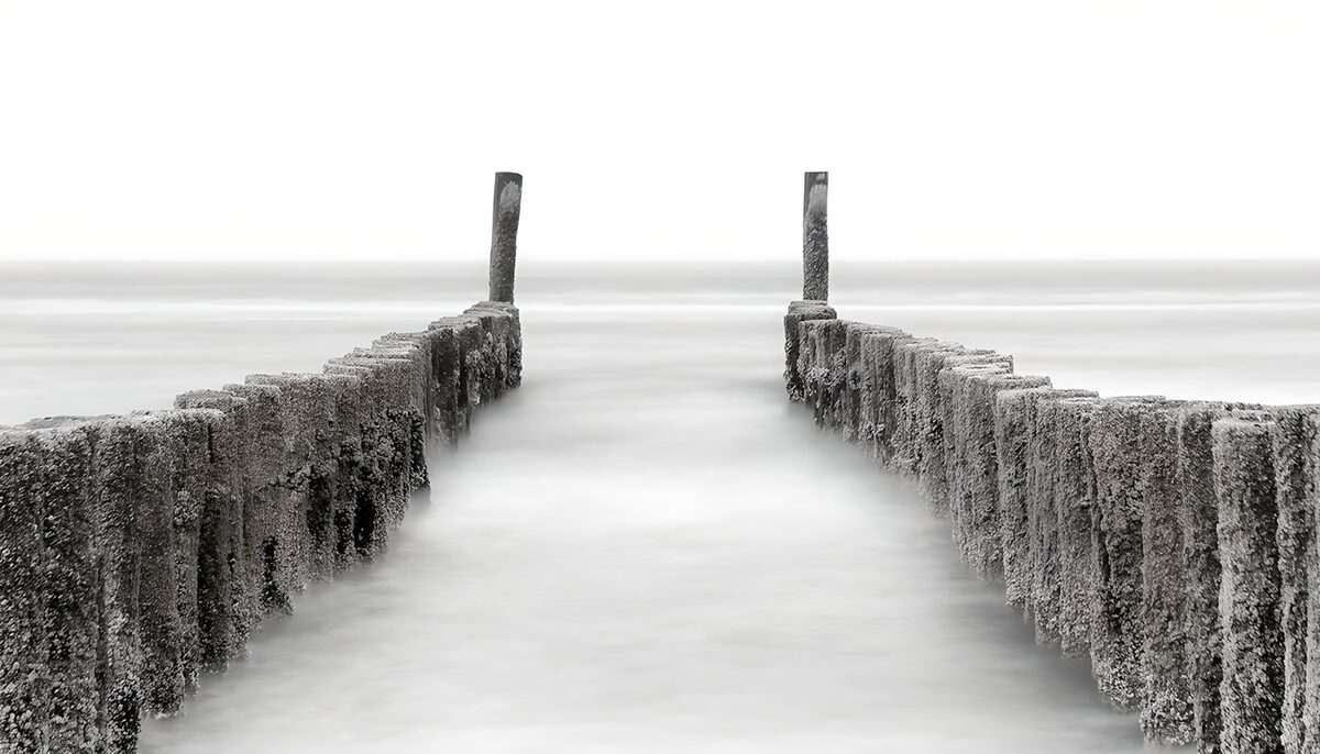 Twee rijen houten palen in stille zee