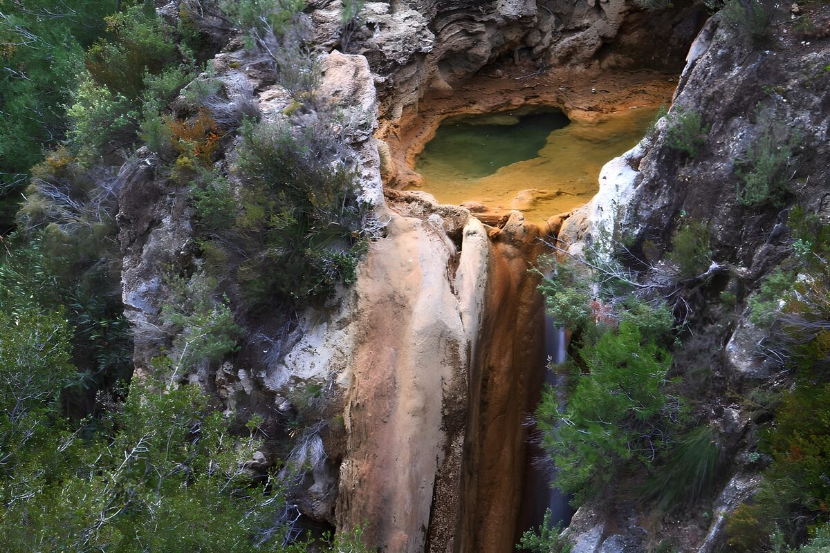 Groene poel boven een smalle waterval