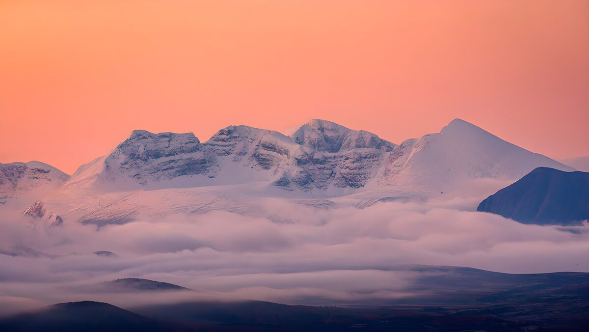 Besneeuwde bergketen onder een roze lucht