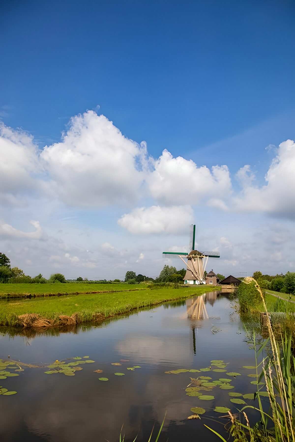 Windmolen aan de sloot onder witte wolken