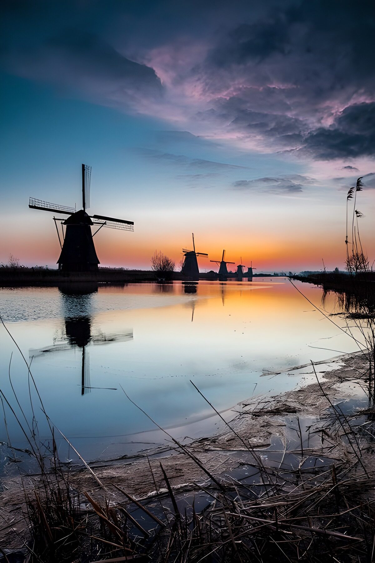 Windmolens aan het water bij zonsondergang