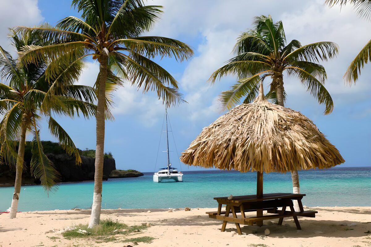 Palmenstrand met parasol en zeilboot