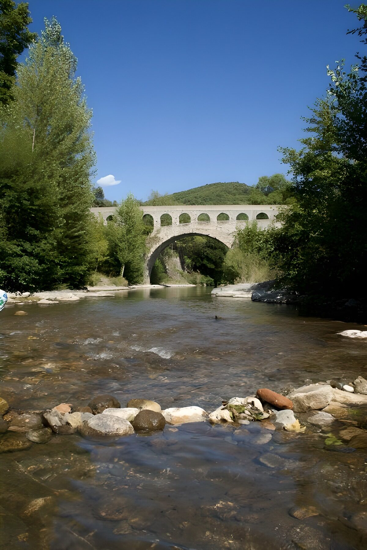 Stenen boogbrug over een zonnige rivier