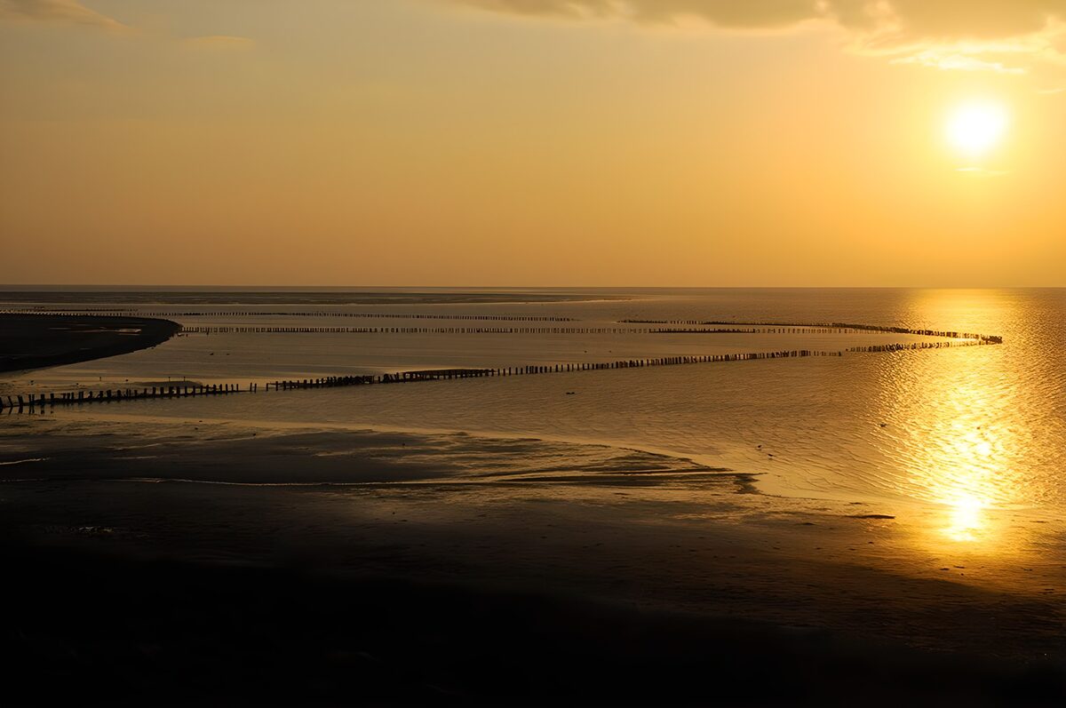 Zonsondergang boven strand en palen