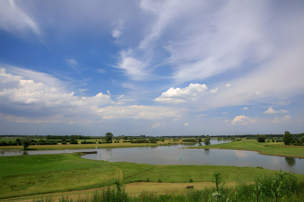 Groene oevers onder een blauwe wolkenlucht