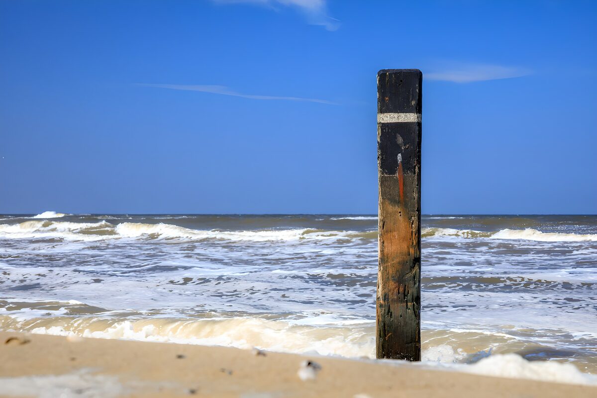 Houten paal in de bruisende branding