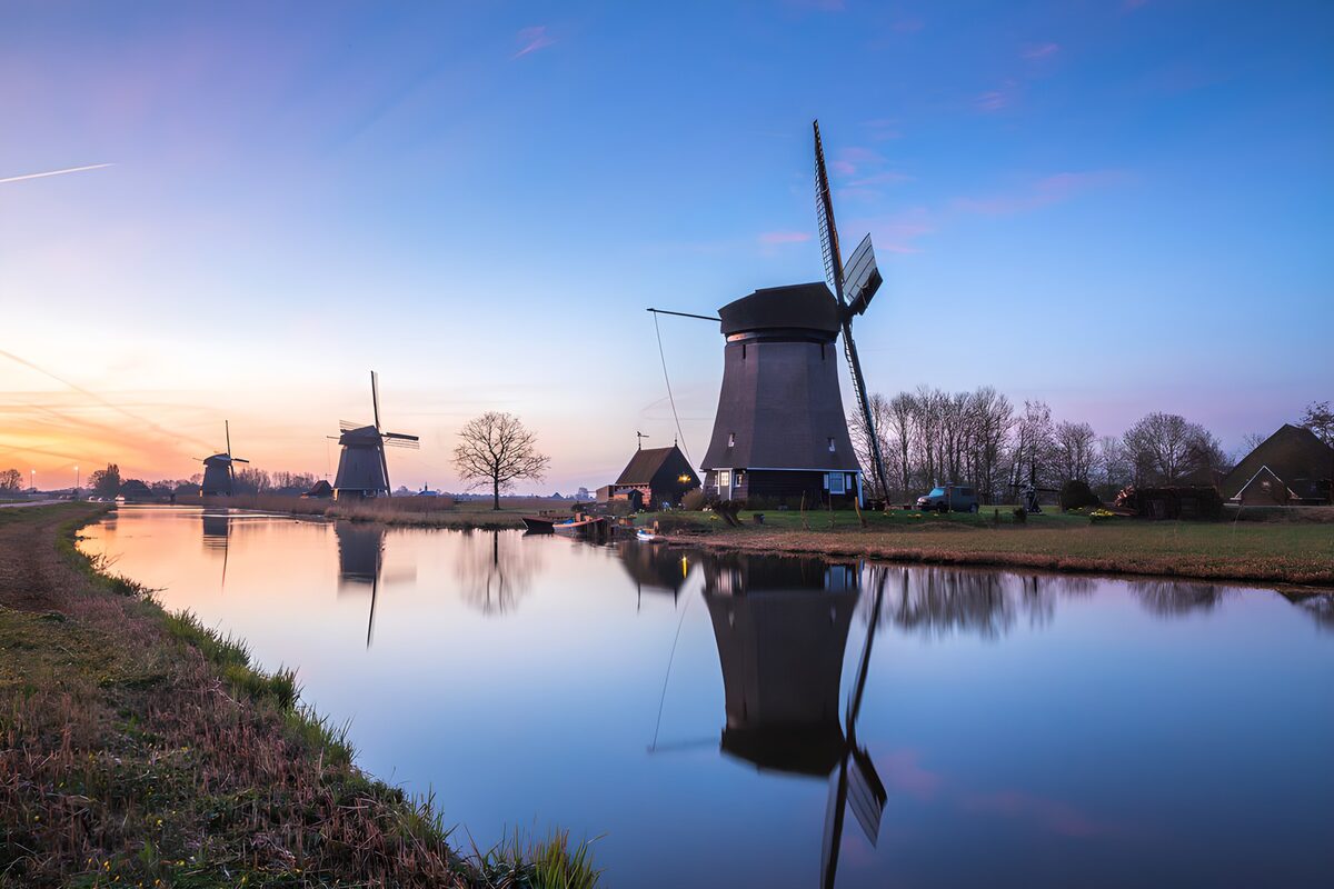 Drie molens aan het water in schemerlicht