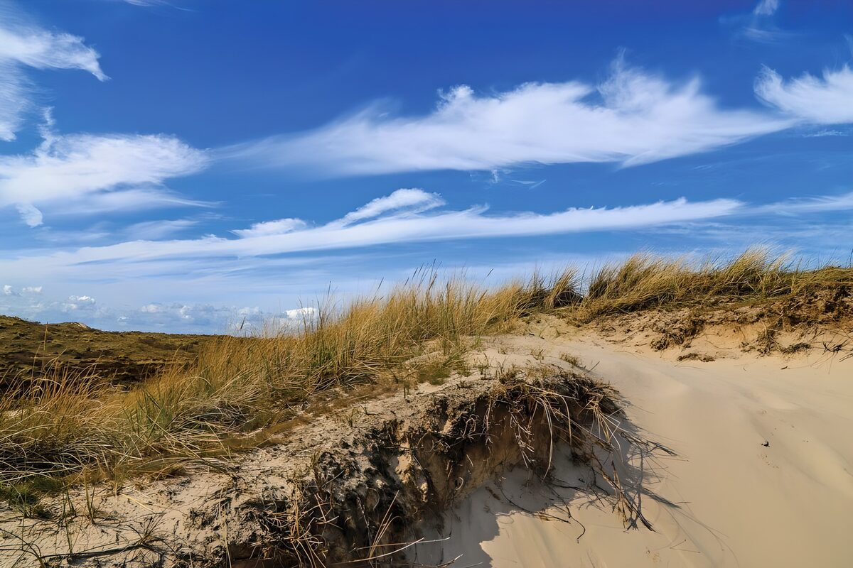 Zandduinen onder een blauwe wolkenlucht