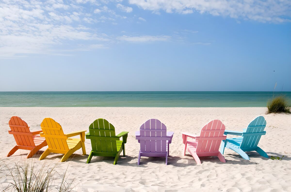 Zes gekleurde strandstoelen aan zee