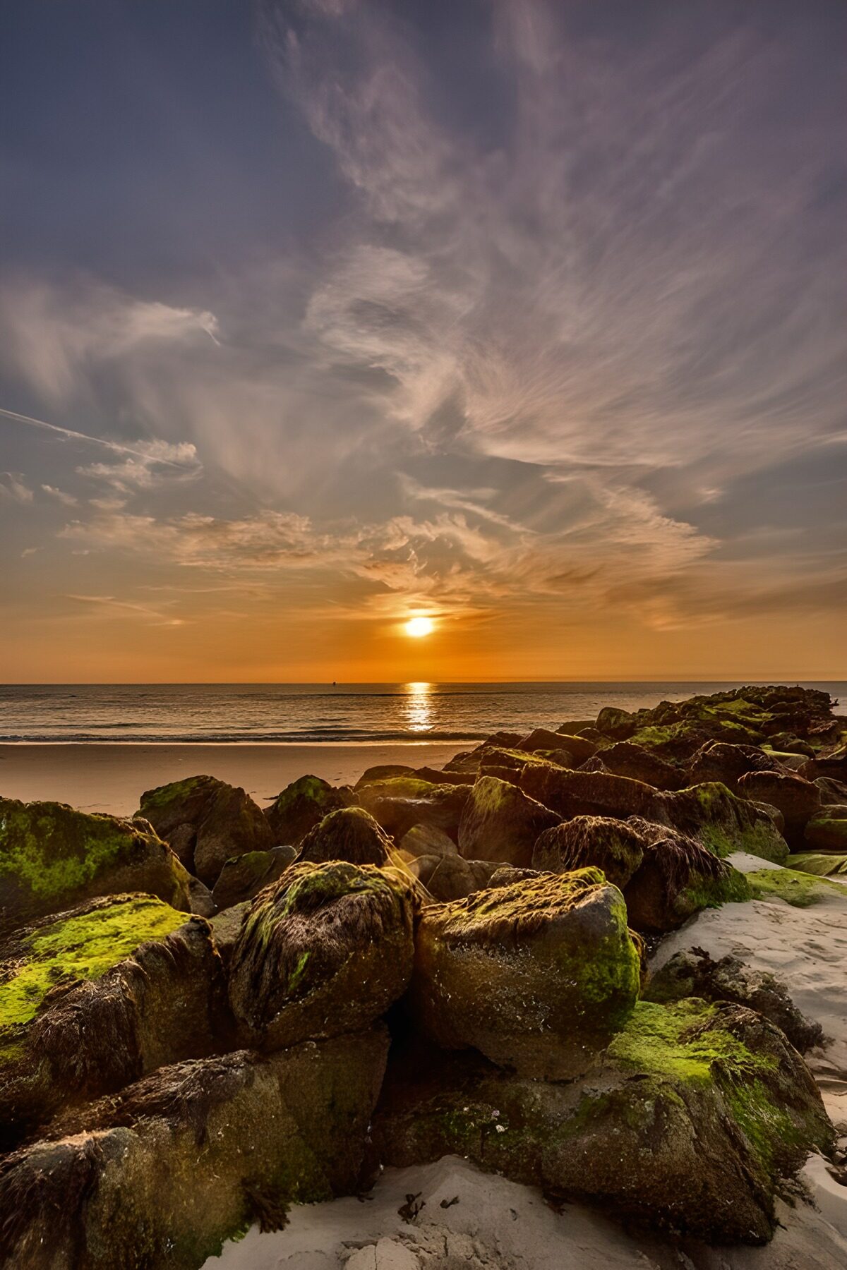 Zonsondergang boven zee en groene rotsen