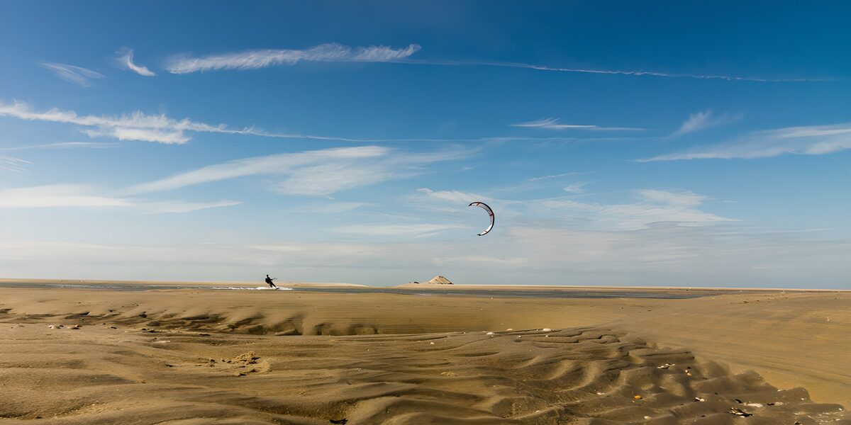 Kitesurfer boven een weids zandstrand