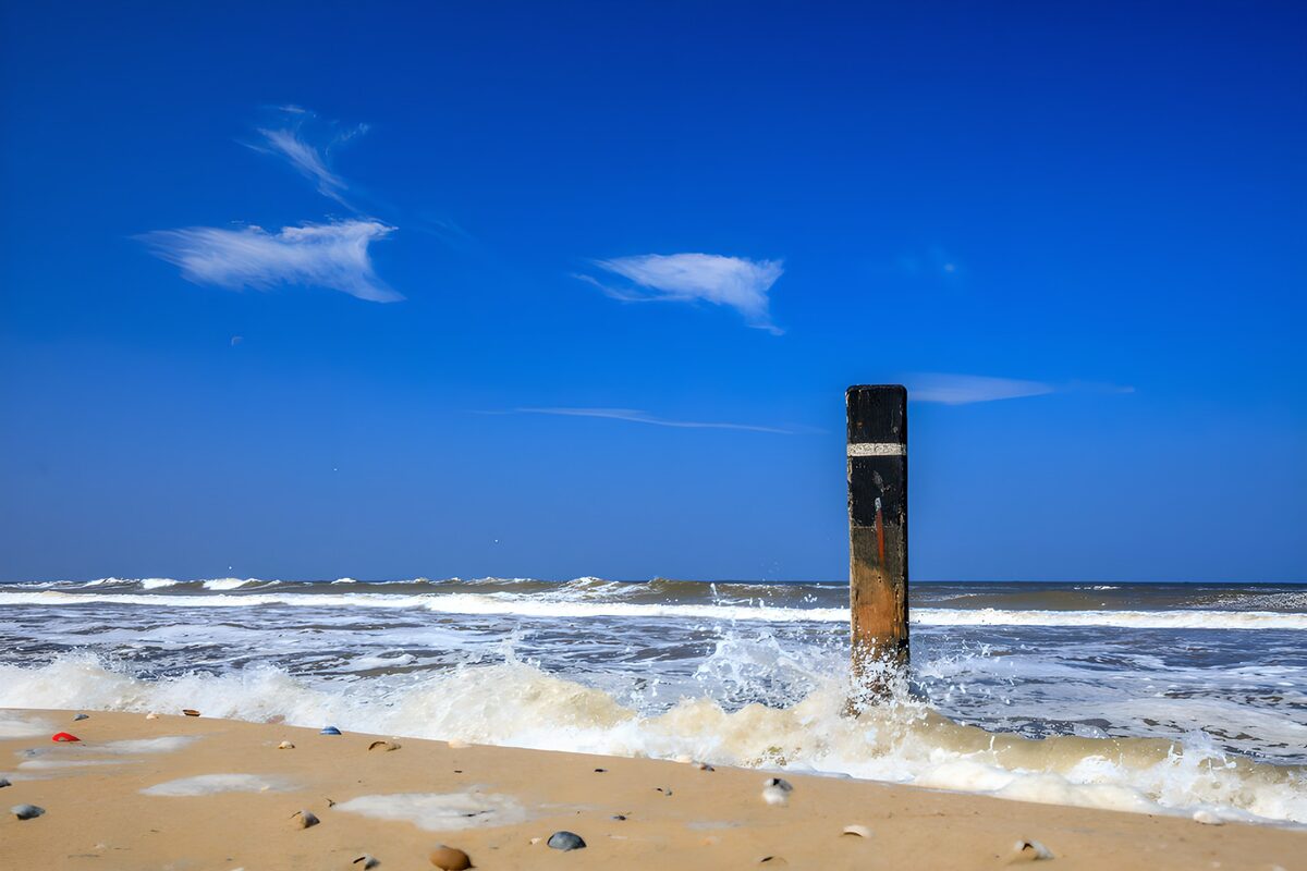 Strandpaal in de schuimende branding