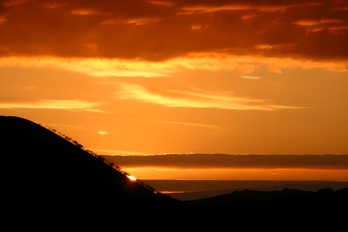 Zonsondergang achter een donkere heuvel