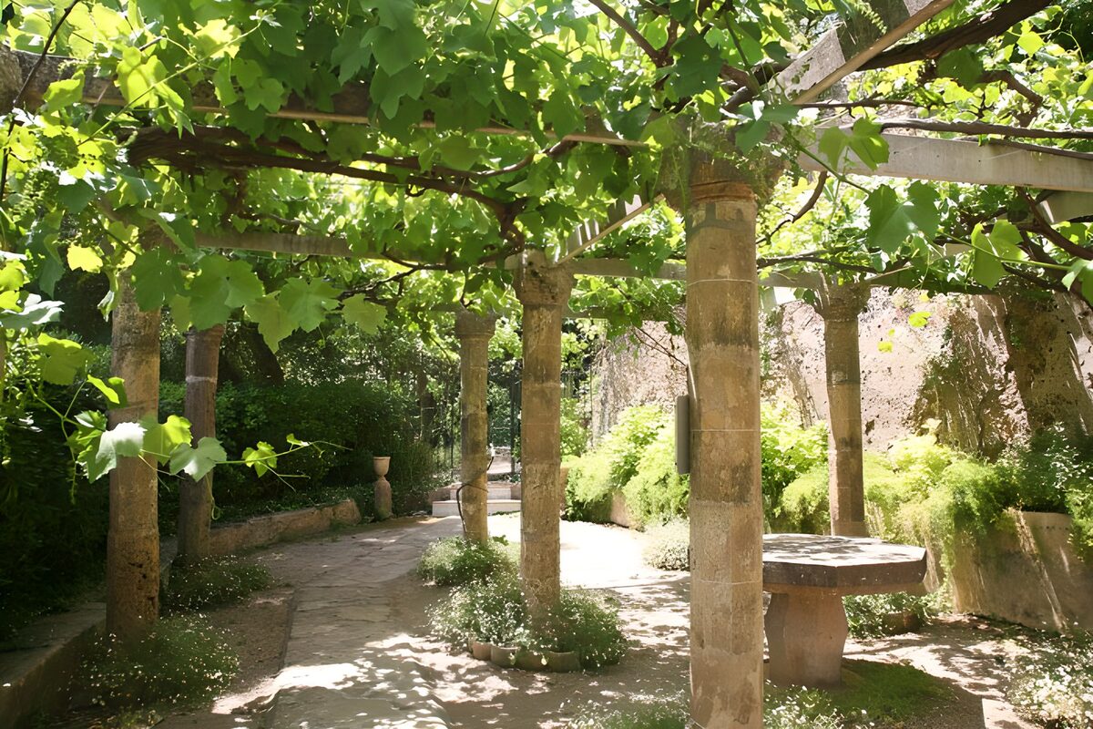 Stenen pergola onder een groen bladerdak