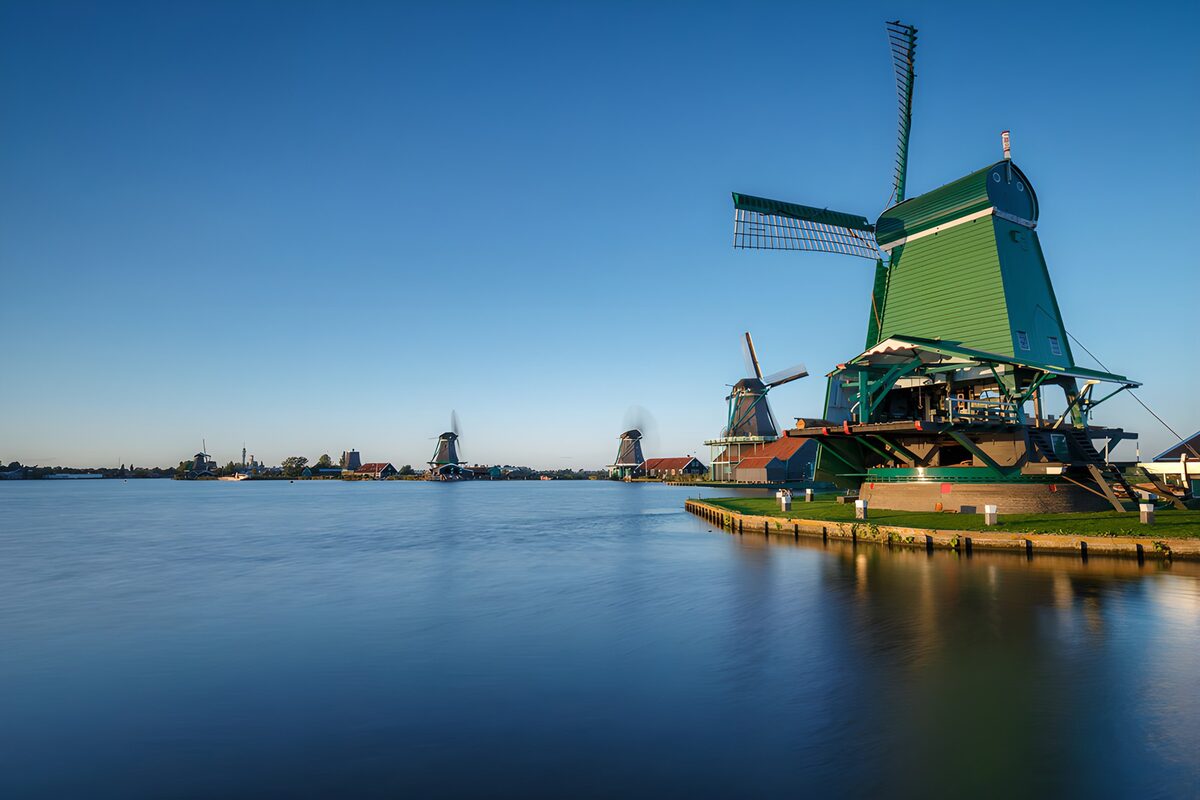 Groene windmolen aan een zonnige oever