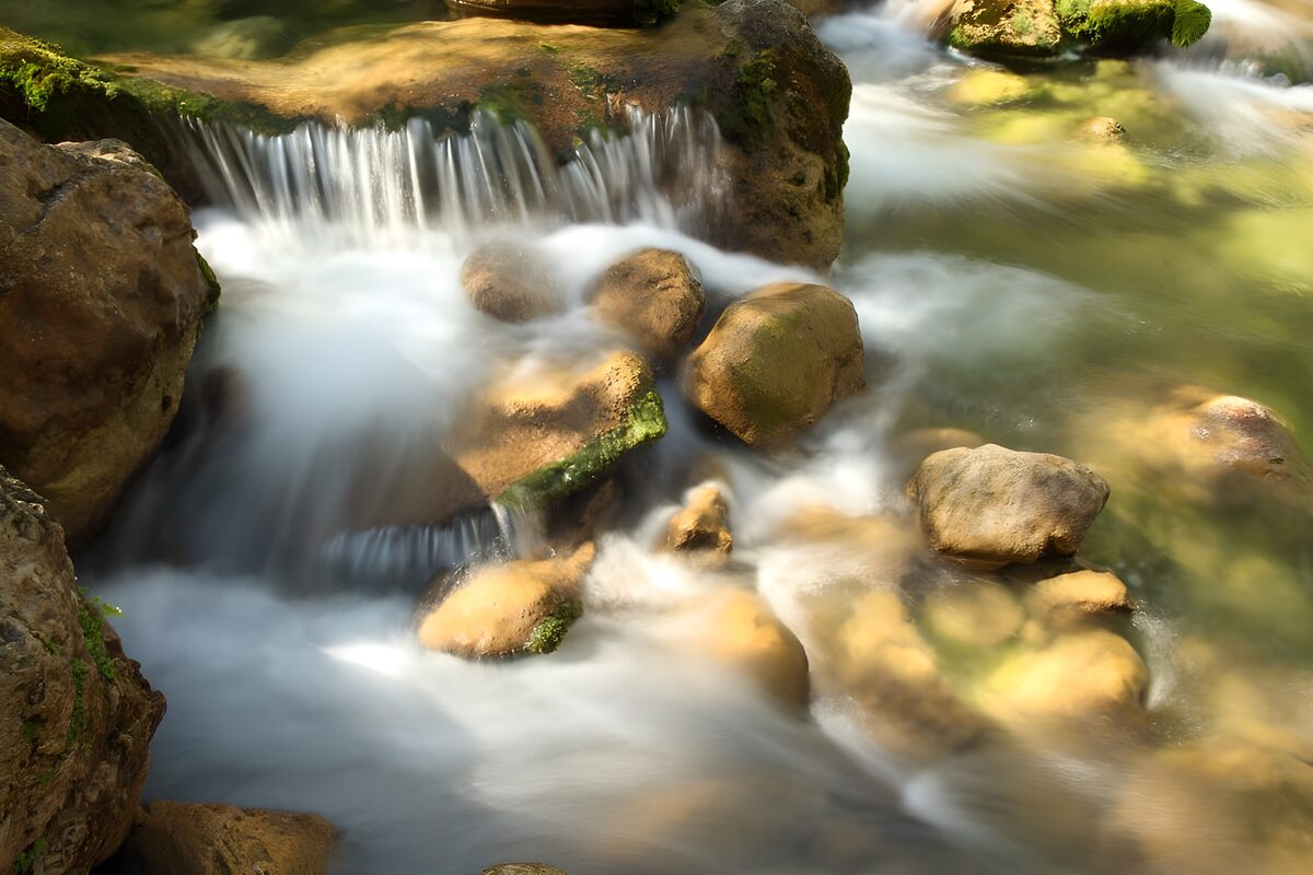 Kleine waterval tussen zonnige keien
