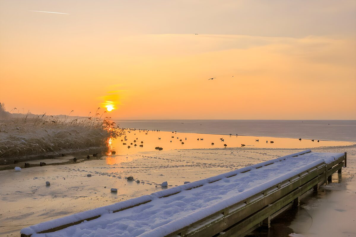 Besneeuwde steiger bij zonsondergang