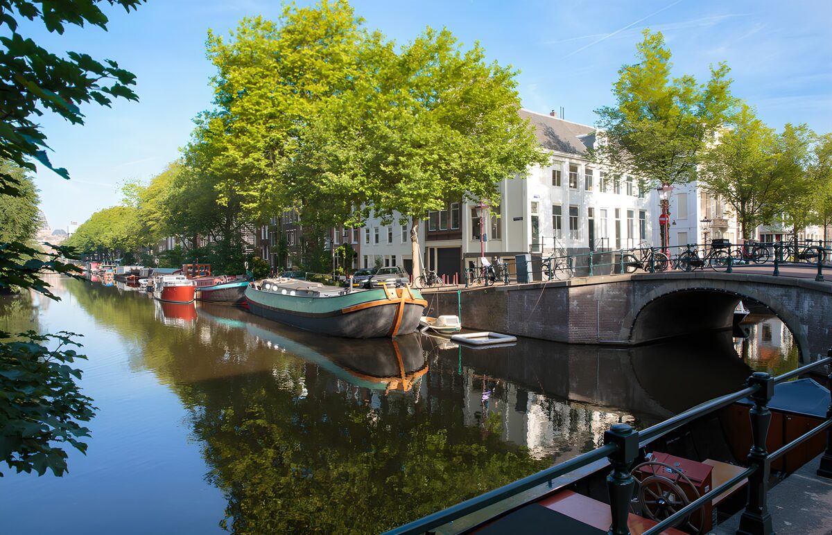 Zonnige gracht met boten en boogbrug