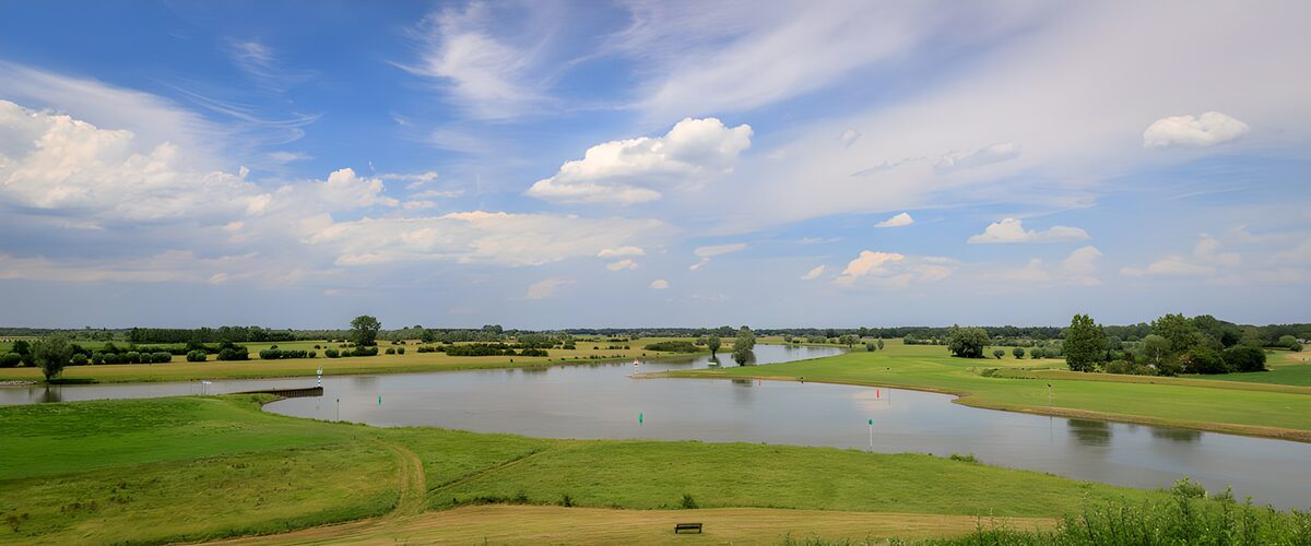 Golfbaan aan het water onder een blauwe lucht