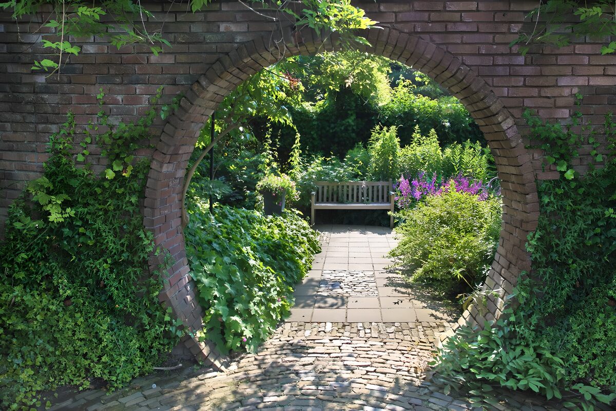 Bakstenen tuinboog met bankje in de zon