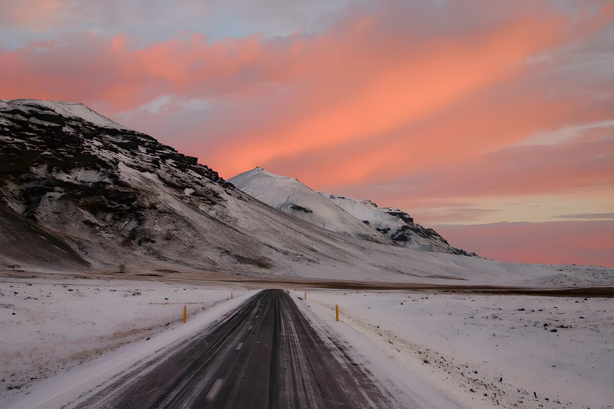 Besneeuwde weg onder een roze lucht